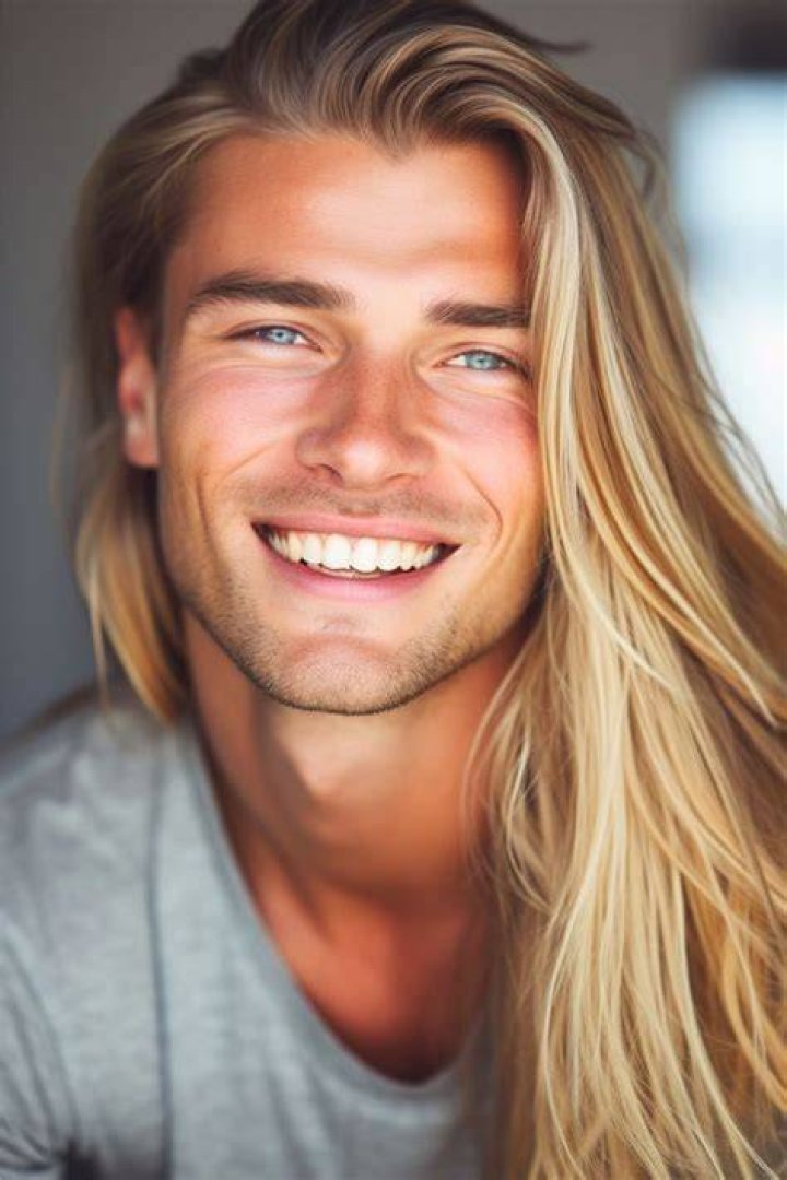 a man with long blonde hair standing next to other people
