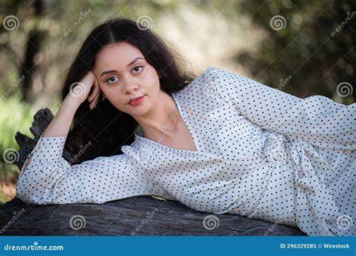a woman laying on top of a bed next to a metal handrail in a room with