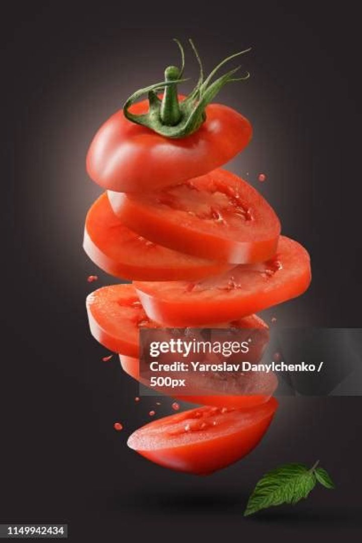 sliced flying tomato with green leaf on black sliced flying tomato