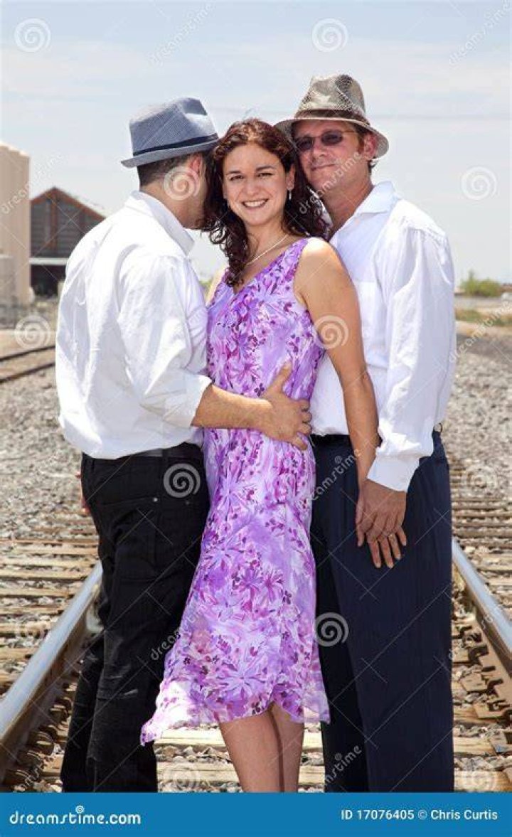 two men and a woman standing next to each other in front of a building