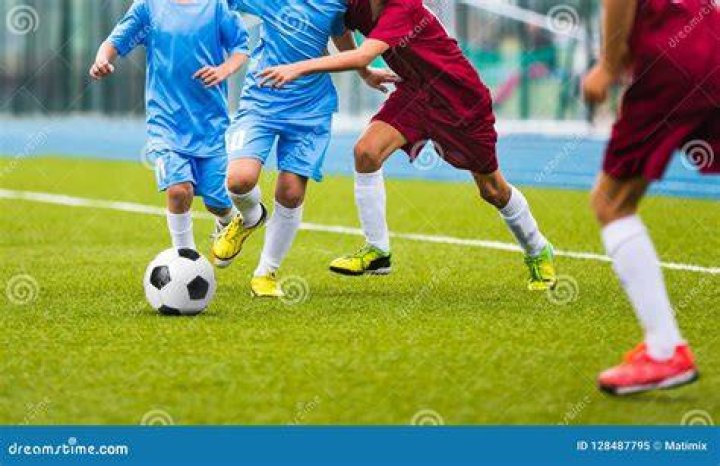 Young soccer players running towards soccer ball. Football soccer game